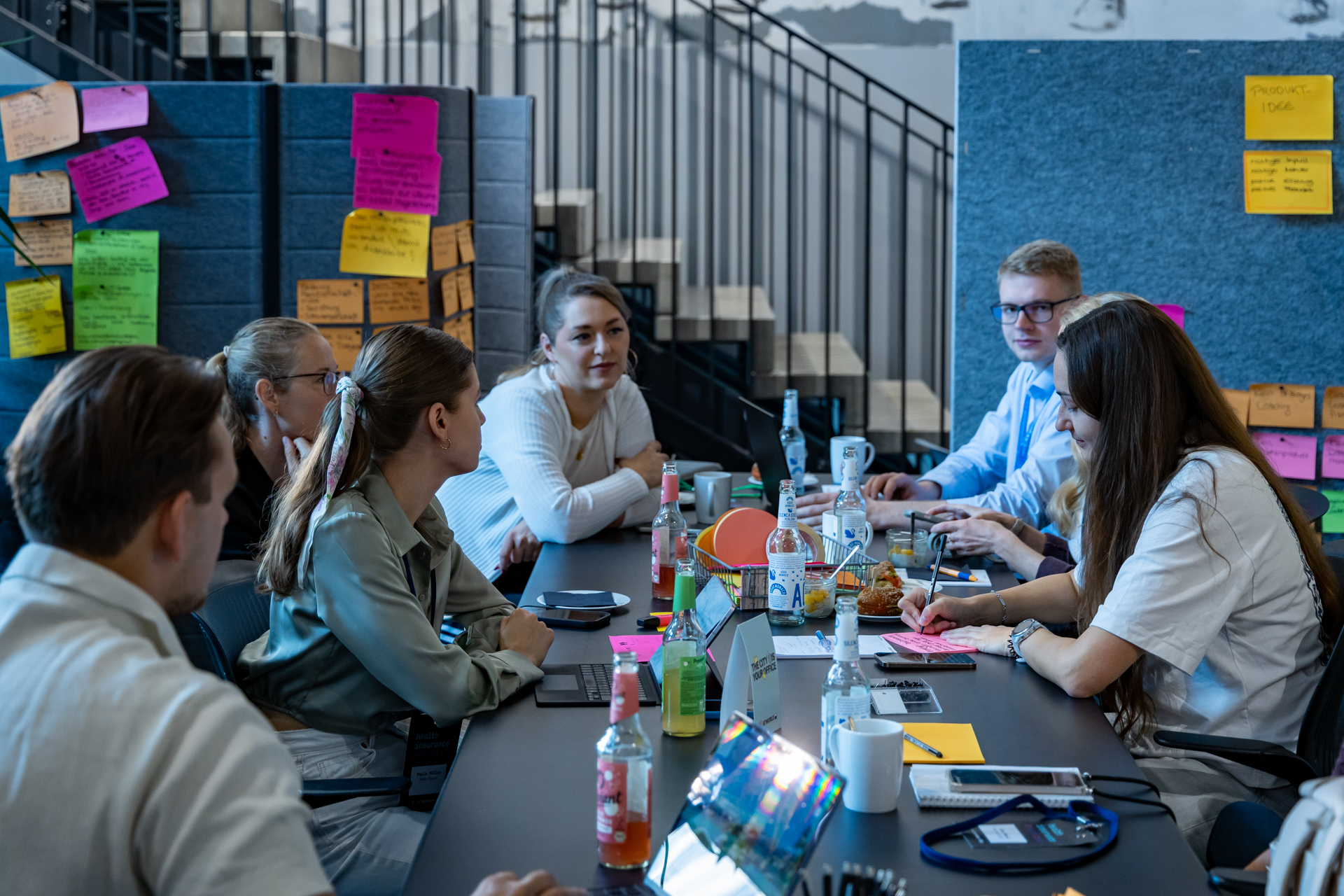 Hackathon-Team arbeitet im Hackspace, im Hintergrund Ideen auf bunten Haftnotizen